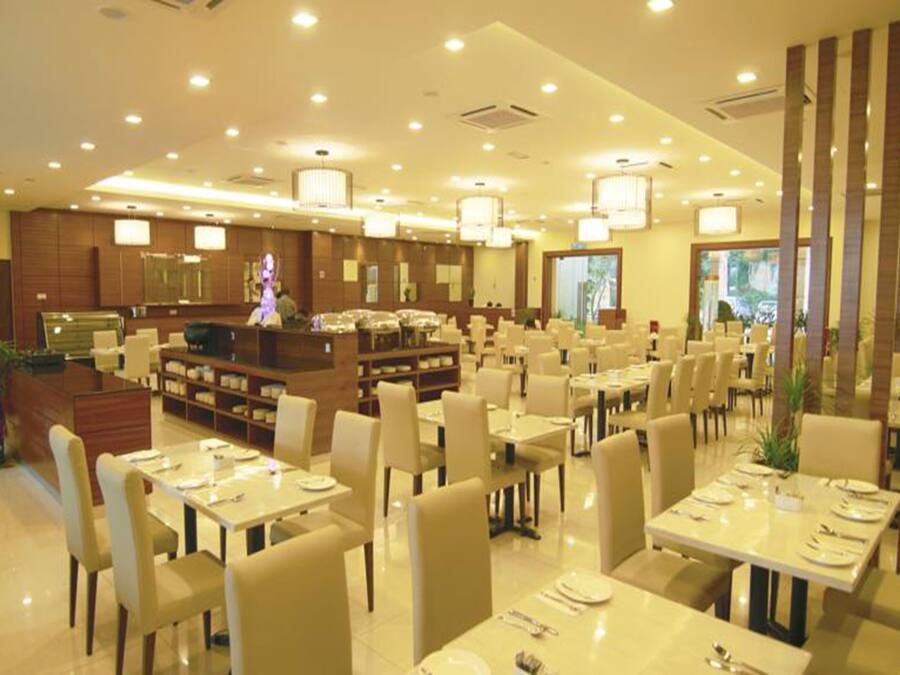 A spacious restaurant with multiple dining tables and chairs, a central counter, and a modern interior design.
