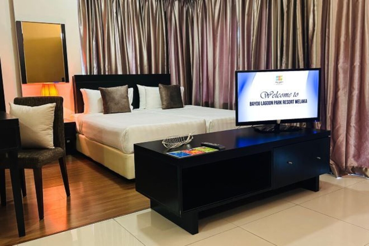 Une chambre d’hôtel avec un lit, une télévision, un bureau et une chaise.