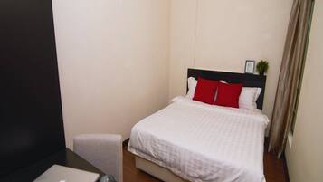 A bedroom with a bed, a desk with a laptop, and a small table with candles.