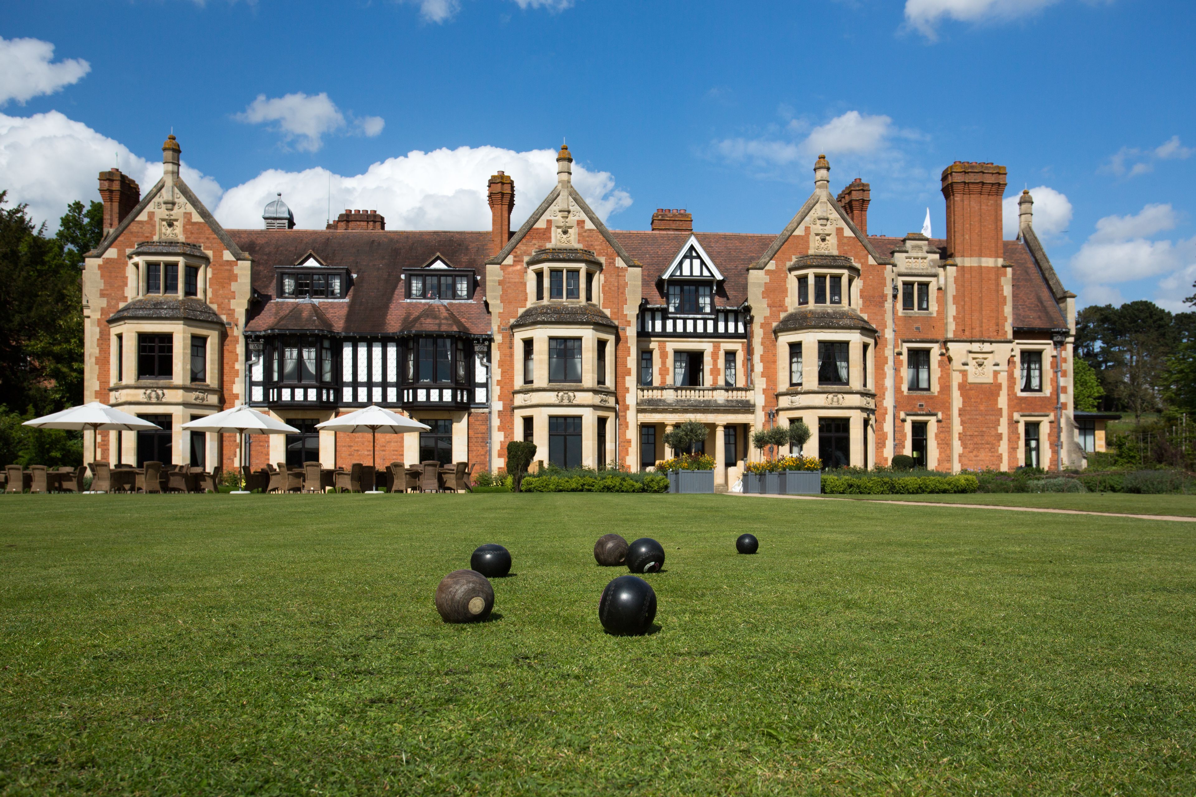 A large, historic building with multiple windows and a well-maintained lawn in front.