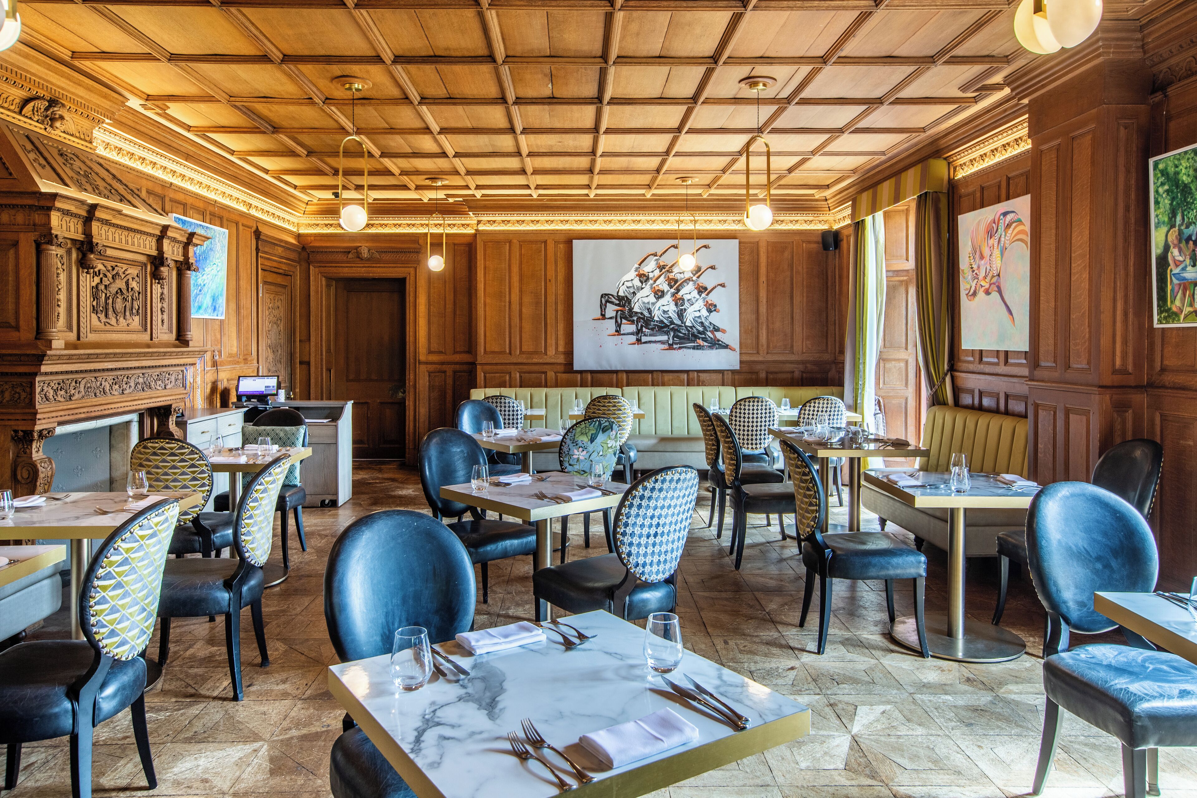 Un restaurante con paneles de madera, mesas con cubierta de mármol y sillas tapizadas en azul.