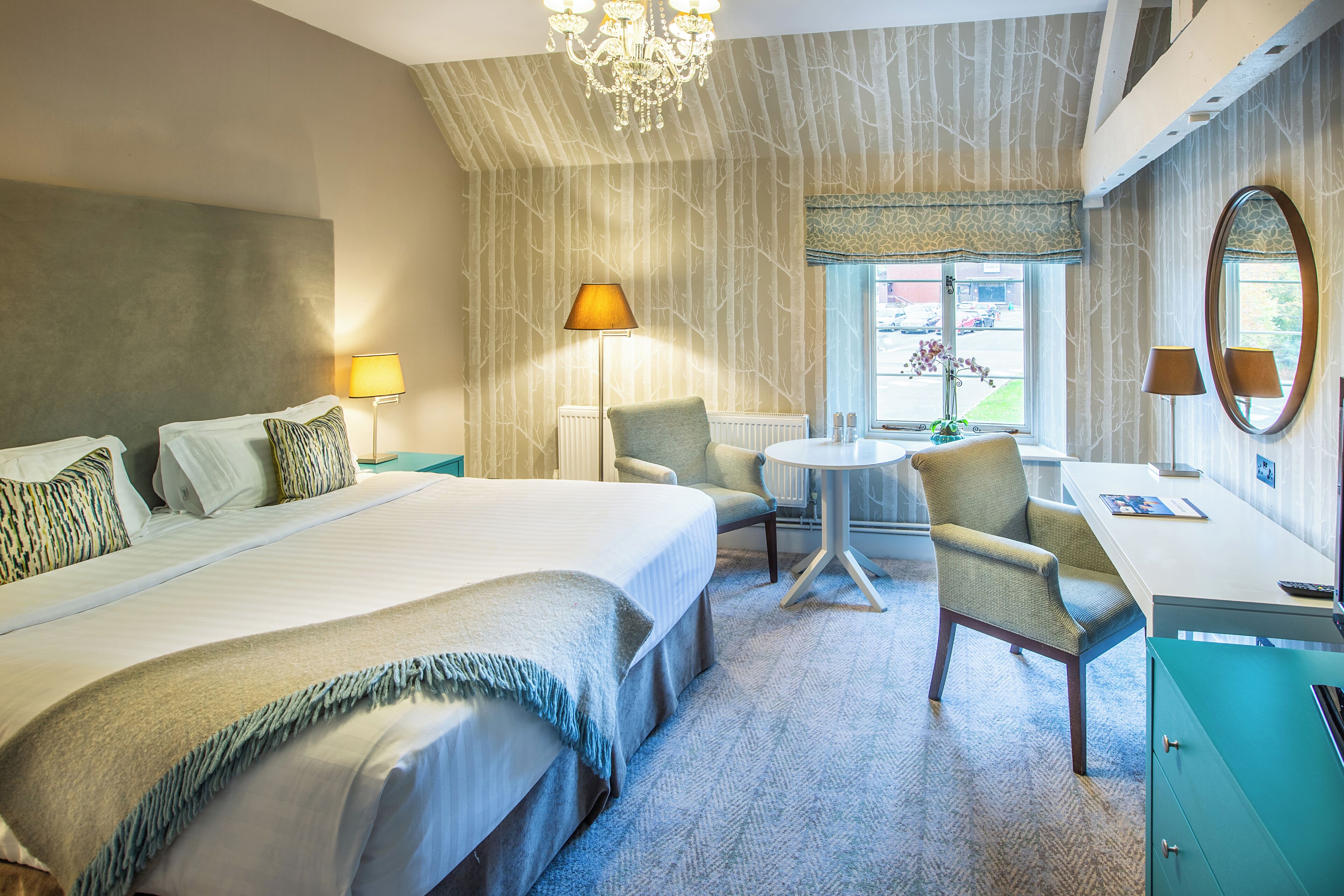 A hotel room with a large bed, a desk, a chair, and a view of the outside.