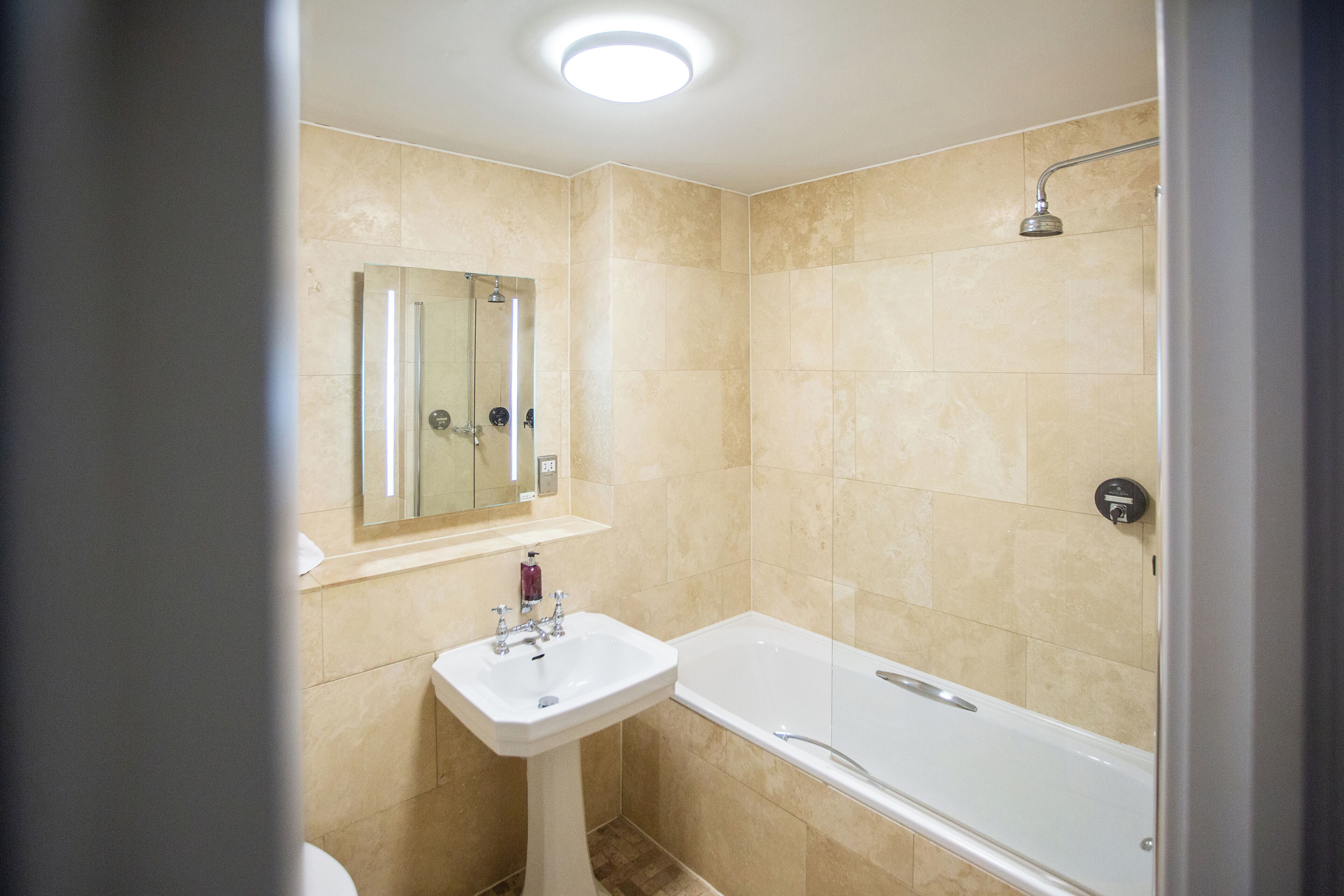 A bathroom with a sink, mirror, and bathtub.