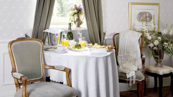 A dining room with a round table set for breakfast, featuring a pitcher, glasses, and a vase of flowers.