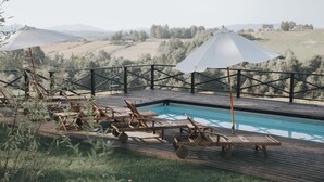 A poolside area with wooden loungers and umbrellas, surrounded by a wooden deck and a view of rolling hills. - Dwór Sieraków (Dobczyce)