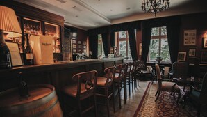 A bar area with wooden furniture, a chandelier, and a view of the outdoors through large windows. - Dwór Sieraków (Dobczyce)