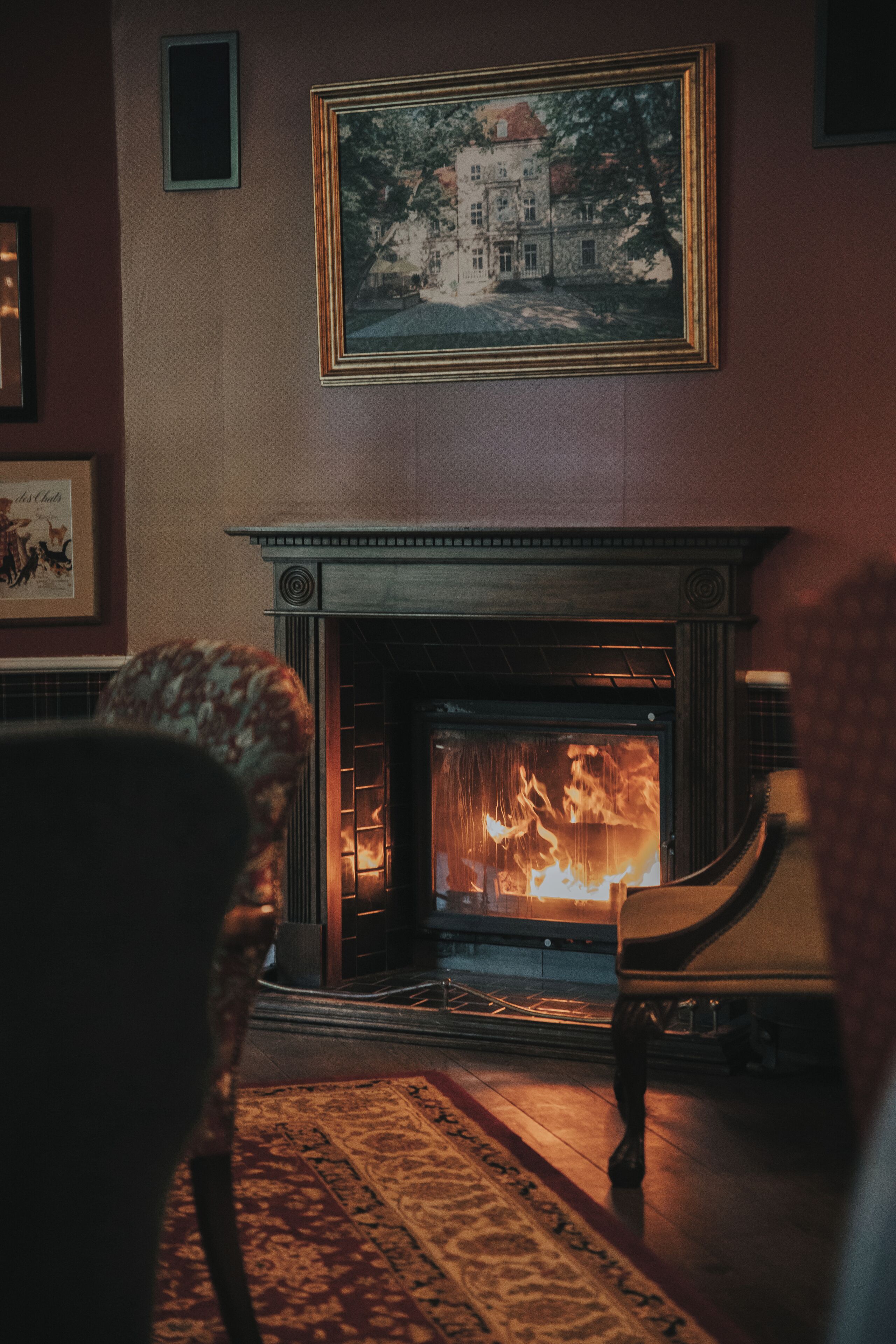 A room with a fireplace, a framed picture on the wall, and a patterned rug on the floor.