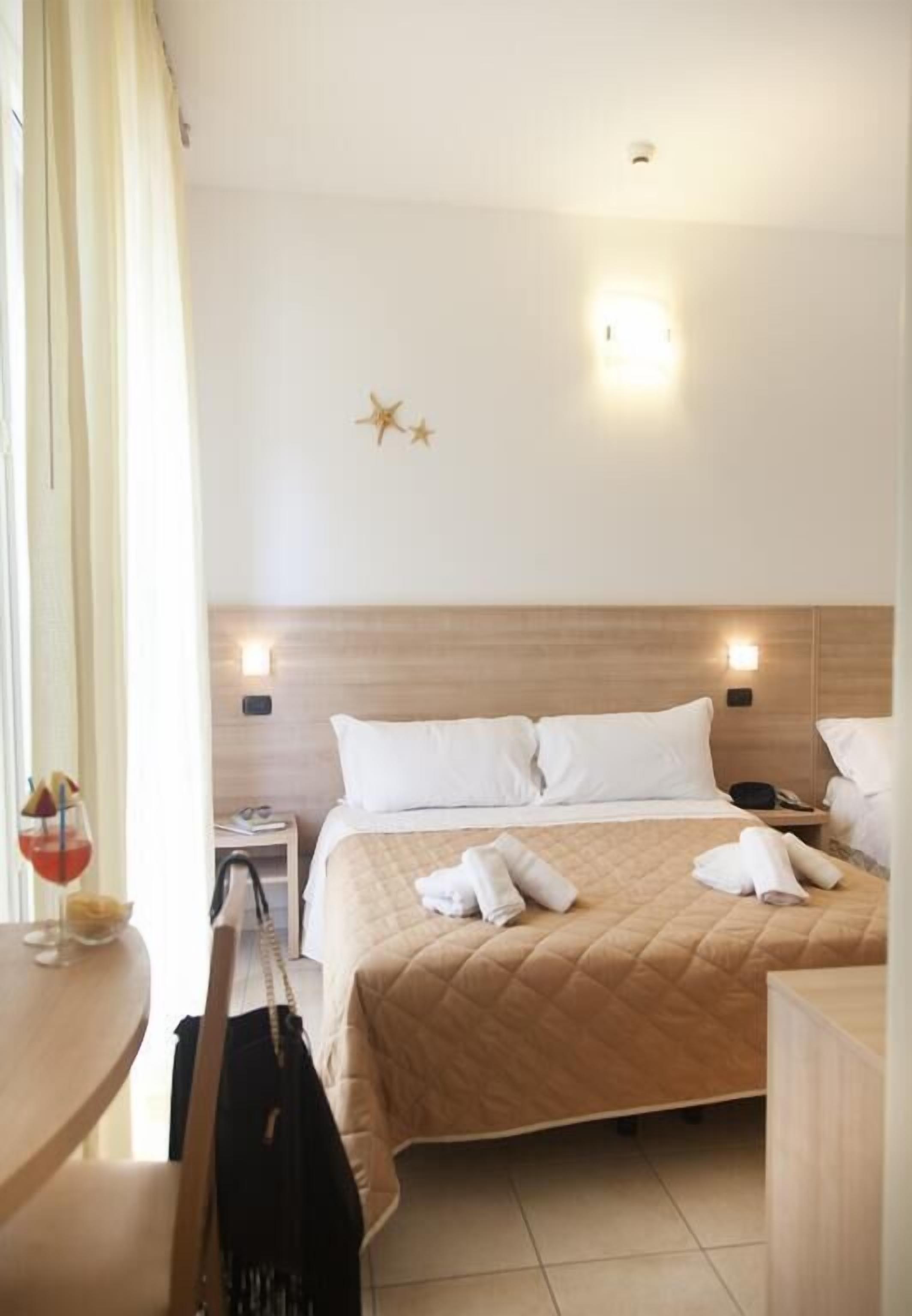 A hotel room with a bed, bedside tables, and a nightstand.