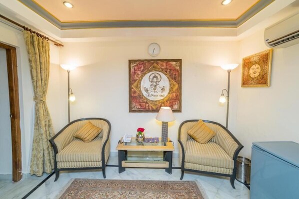 A room with two armchairs, a small table with a lamp, a clock, and framed artwork on the wall.