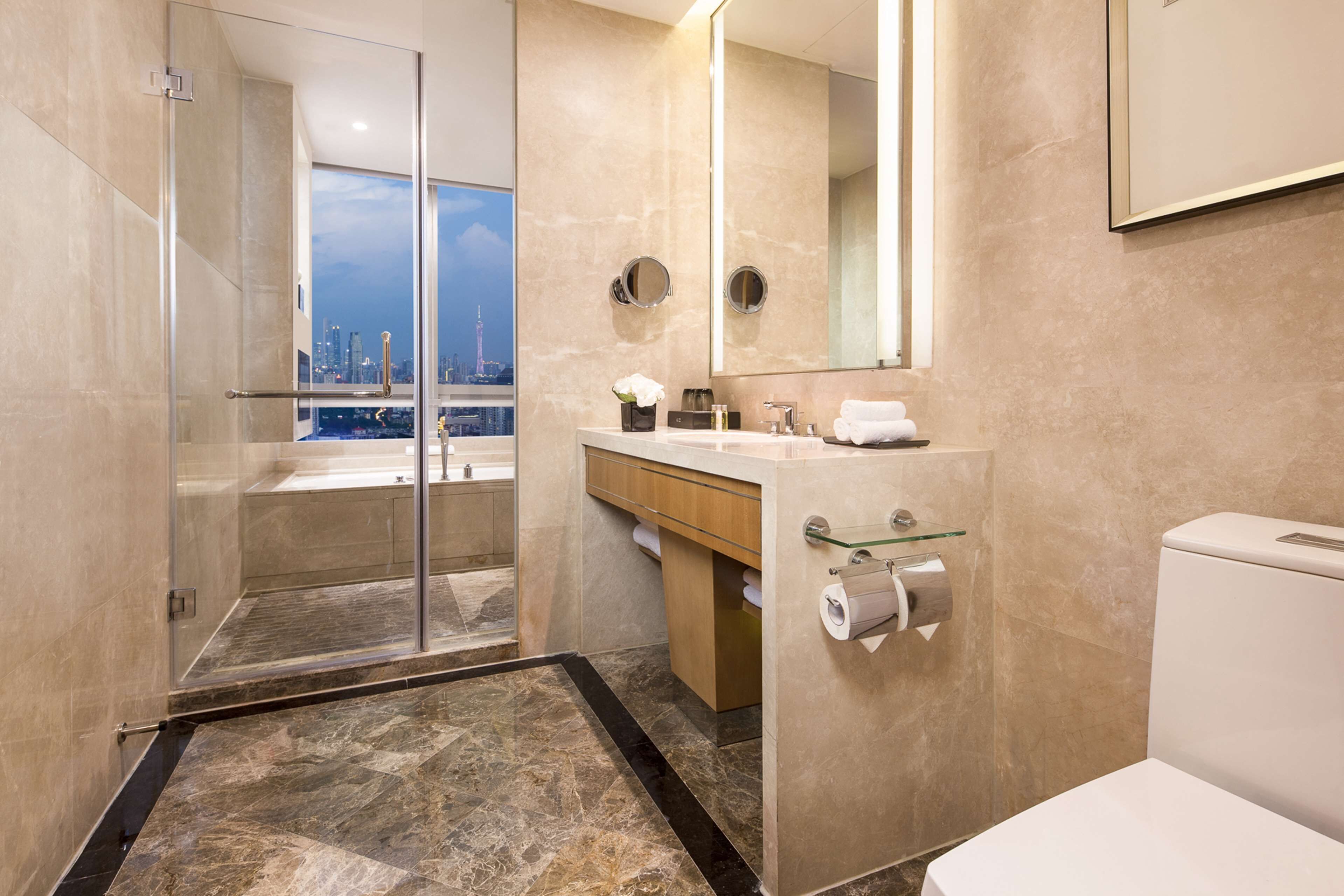 Un bagno moderno con cabina doccia in vetro, un mobile lavabo con specchio e il water.