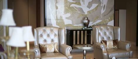 Un salón lujoso con dos sillones cómodos, una mesita redonda y un jarrón decorativo.