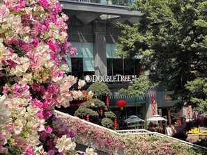 Un hotel DoubleTree con una fachada moderna, un balcón con plantas y mobiliario exterior.
