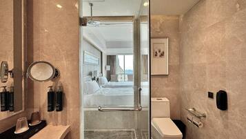 A modern bathroom with a glass shower enclosure, a toilet, and a sink area with toiletries.