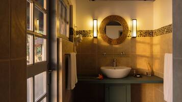 Une salle de bain avec une grande fenêtre, un lavabo, un miroir et un porte-serviettes.