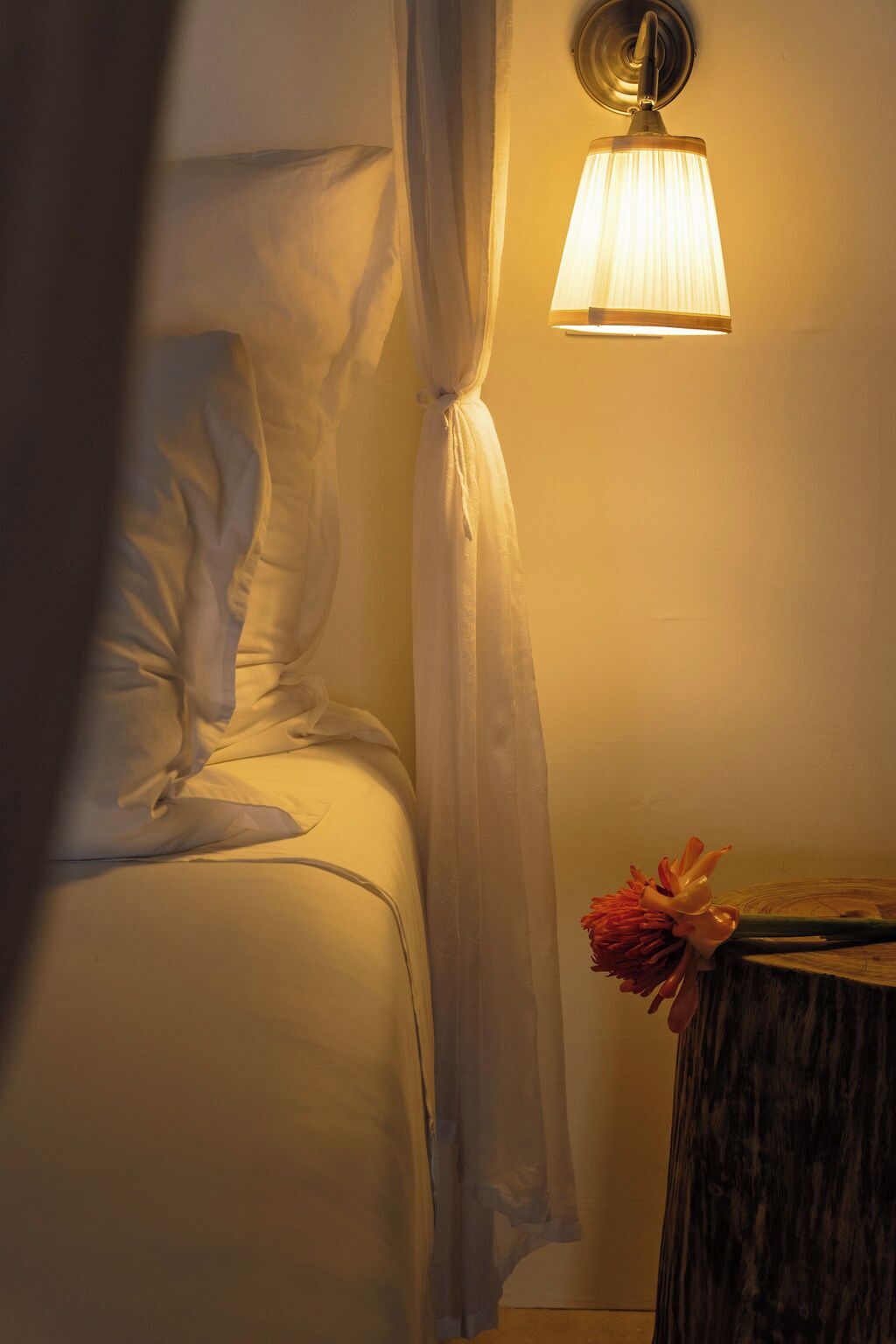 Une chambre à coucher avec un lit, une table de chevet, une lampe et un rideau.