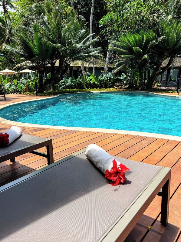 Alberca al aire libre, sombrillas en la alberca y camastros 