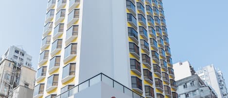A tall Travelodge hotel with a prominent 'Travelodge' sign on the facade, a covered entrance, and a modern architectural design.