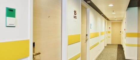 A hotel corridor with doors marked with room numbers, carpeted flooring, and recessed lighting.