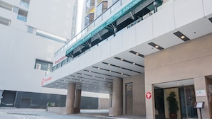 A modern building with a covered entrance, a sign for Oak Tree Restaurant, and a Travelodge logo.