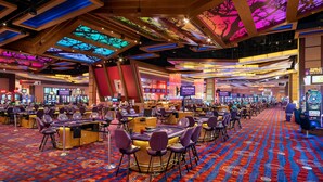 A casino interior with multiple gaming tables, chairs, and slot machines.