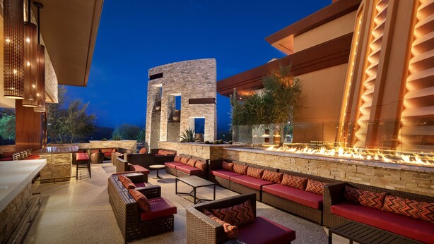 An outdoor patio with a fire feature, seating, and a stone wall.