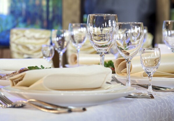 A table set with multiple wine glasses, plates, and cutlery, suggesting a formal dining setting.
