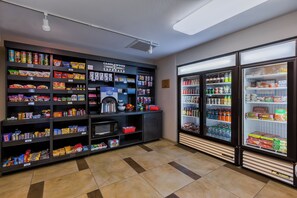 A snack and beverage vending area with various snack options and a refrigerated beverage section. - Candlewood Suites Tucson by IHG (Tucson)