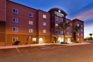 A multi-story hotel building with a prominent sign reading 'CANDLEWOOD SUITES.' There are multiple windows on each floor, and the entrance is illuminated. - Candlewood Suites Tucson by IHG (Tucson)