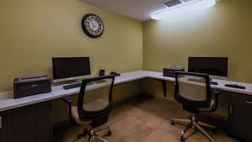 A conference room with two desks, chairs, a clock, and a printer.