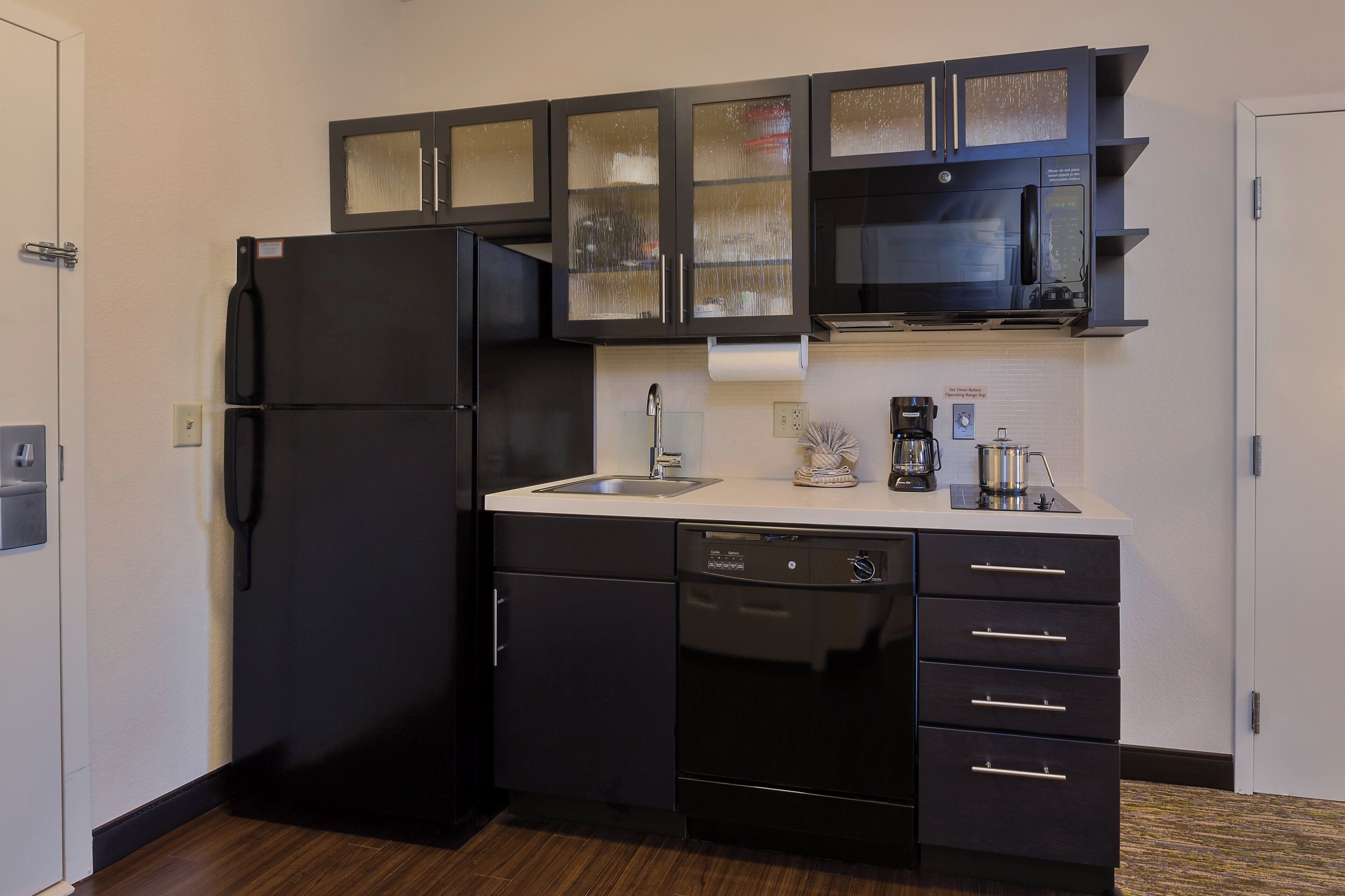 A compact kitchen with a black refrigerator, a built-in microwave, and a dishwasher.