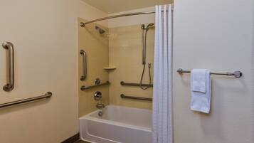 A bathroom with a bathtub, shower, grab bars, and a towel rack.
