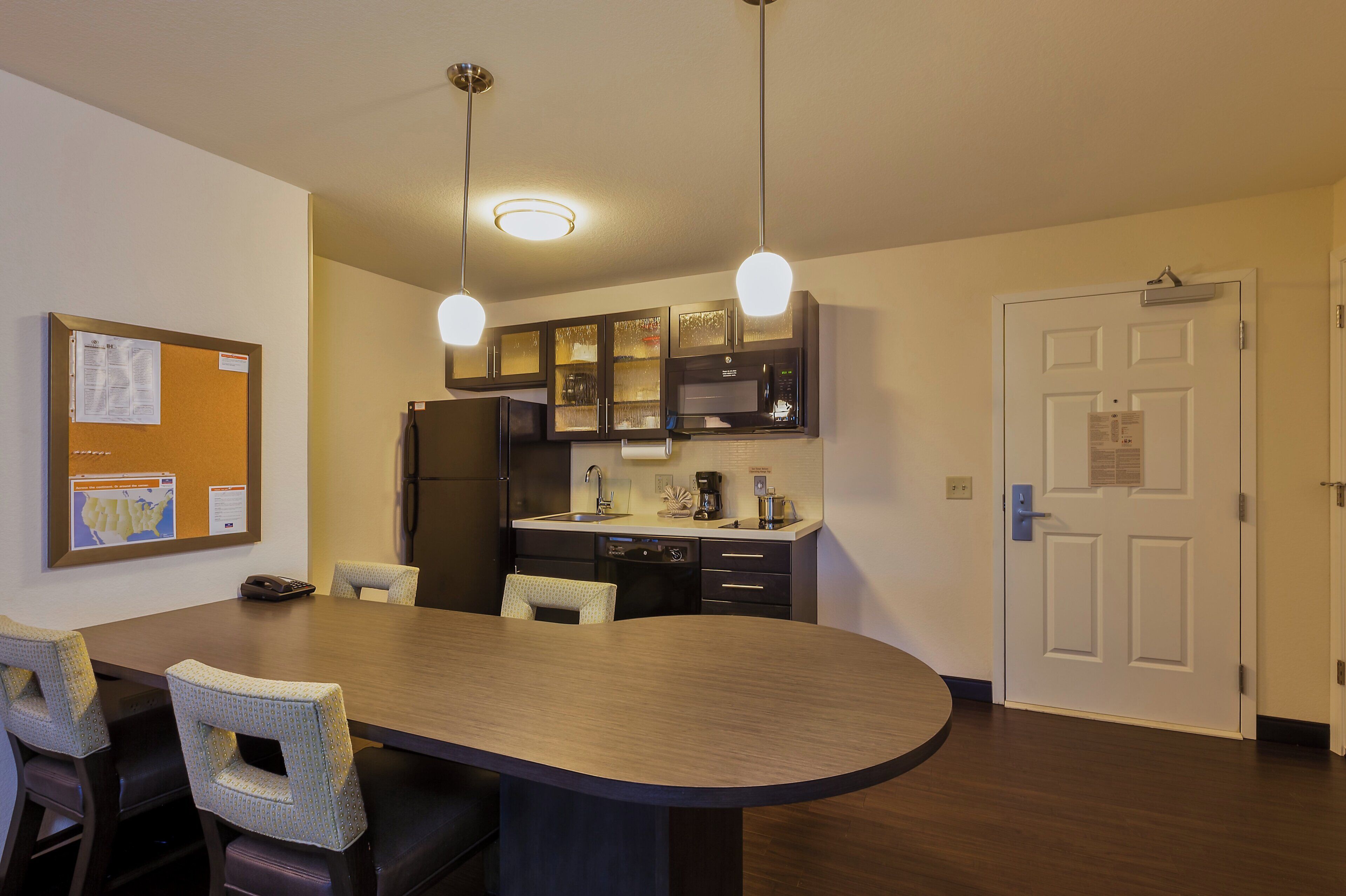 A modern kitchen with a dining table, chairs, and a refrigerator.