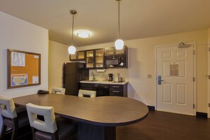 A modern kitchen with a dining table, chairs, and a refrigerator. - Candlewood Suites Tucson by IHG (Tucson)