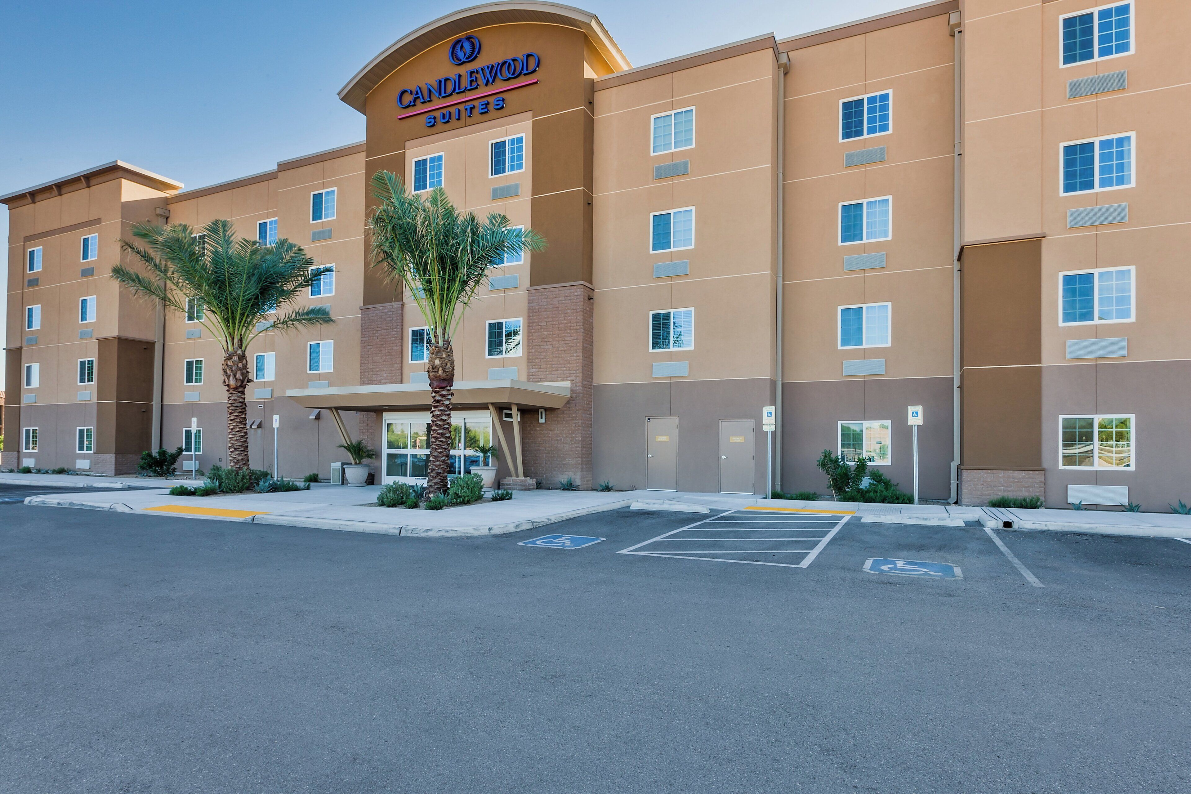 A hotel with a sign reading 'CANDLEWOOD SUITES' and a parking lot with handicapped parking spaces.