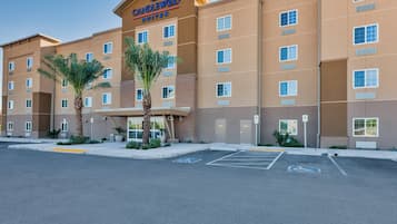 A hotel with a sign reading 'CANDLEWOOD SUITES' and a parking lot with handicapped parking spaces.
