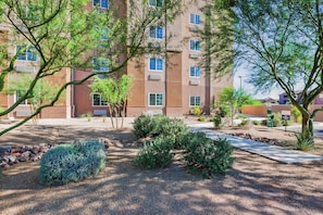 A multi-story building with a landscaped garden area featuring shrubs and trees. - Candlewood Suites Tucson by IHG (Tucson)