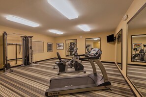 A hotel gym with exercise equipment, including a treadmill and a weight machine, carpeted flooring, and mirrors on the walls. - Candlewood Suites Tucson by IHG (Tucson)