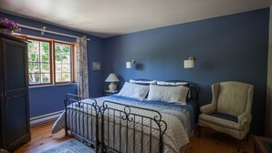 Une chambre à coucher avec un lit, une chaise, une table de chevet et une fenêtre avec des rideaux.