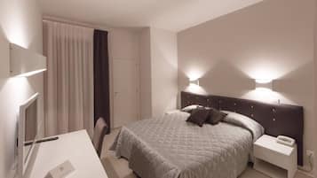 Relax in a serene space with a neatly made bed, flat-screen TV, and desk for work.