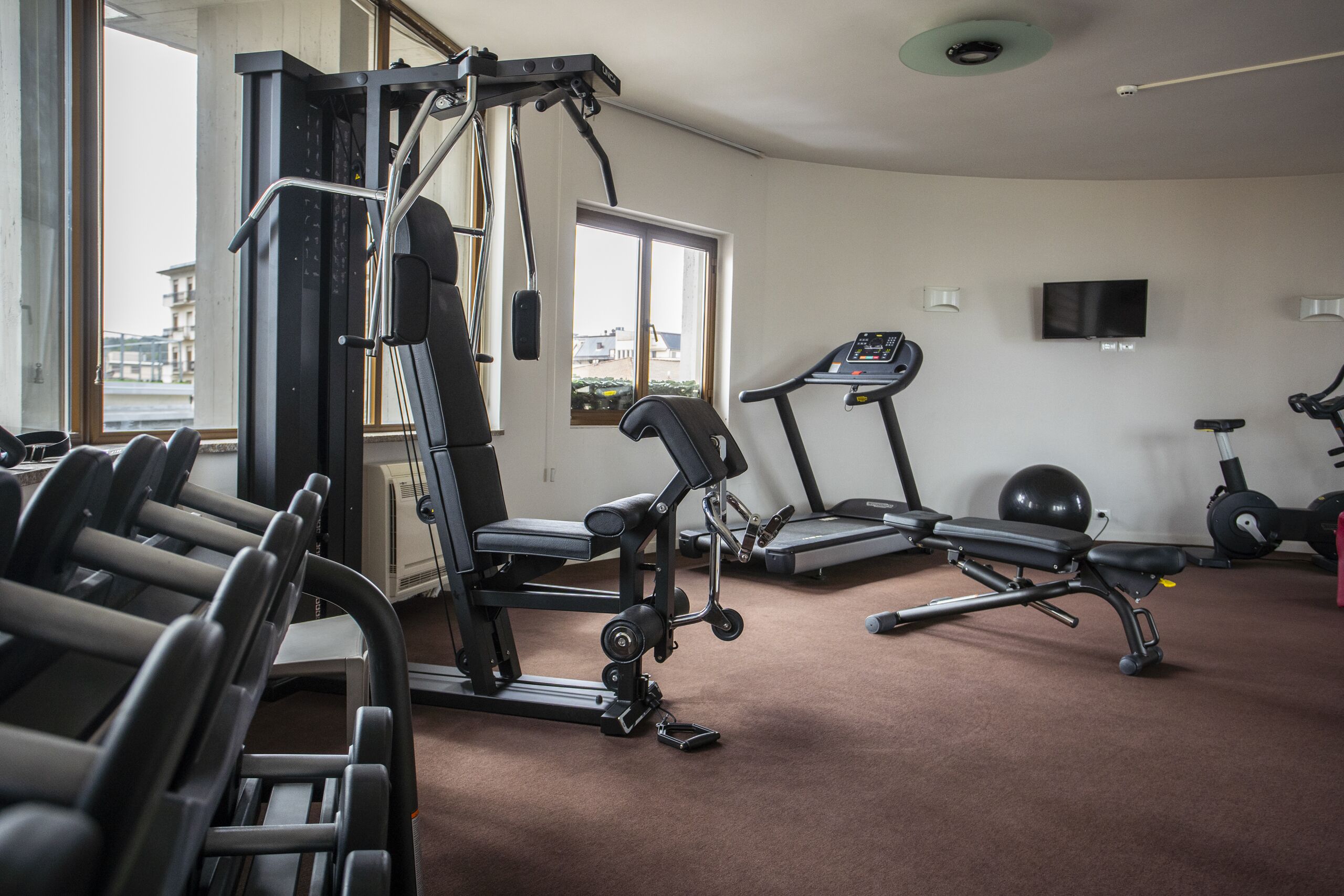 Ein Fitnessraum mit Trainingsgeräten, Laufband und stationärem Fahrrad.