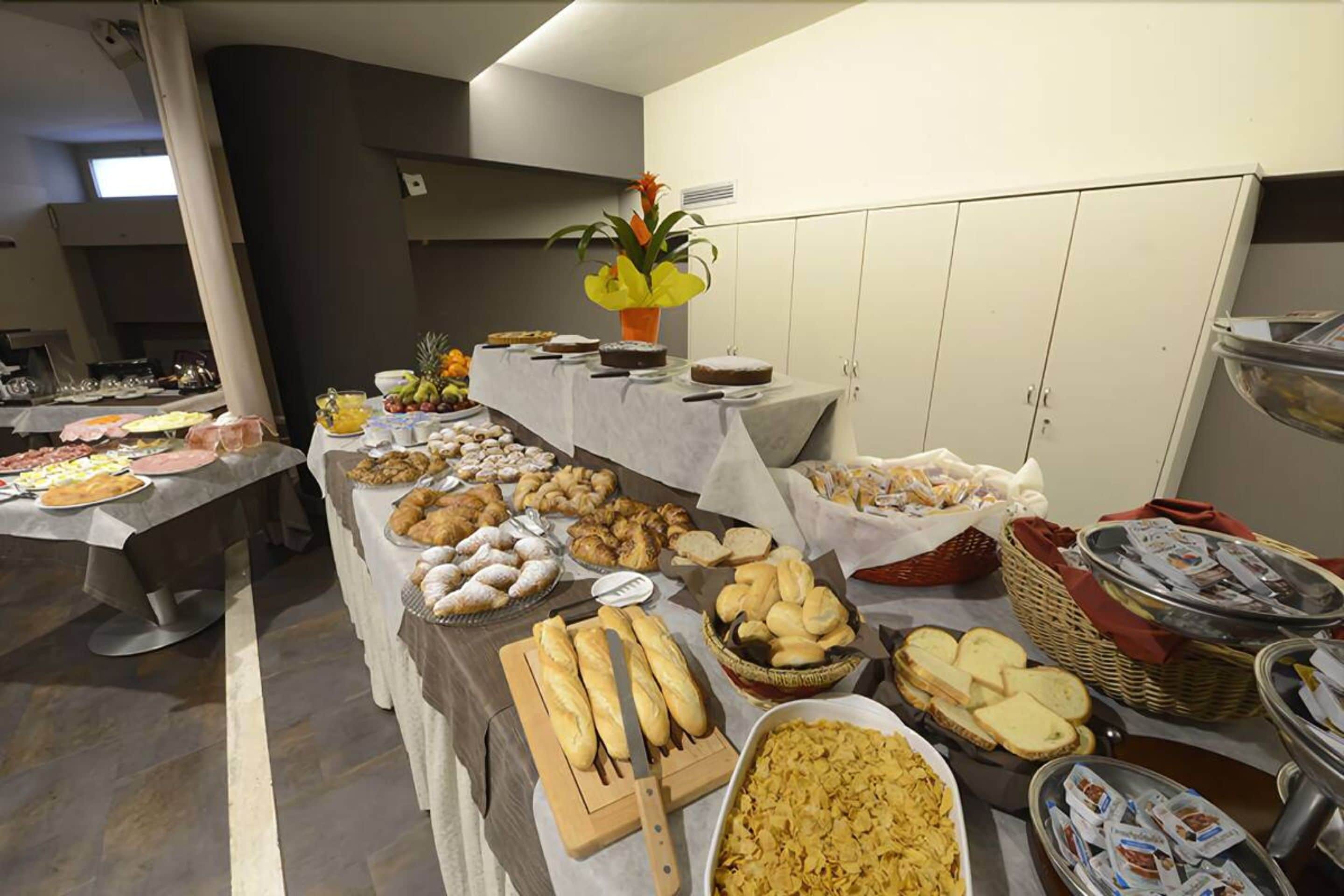 A buffet with various food items including bread, pastries, and fruits.