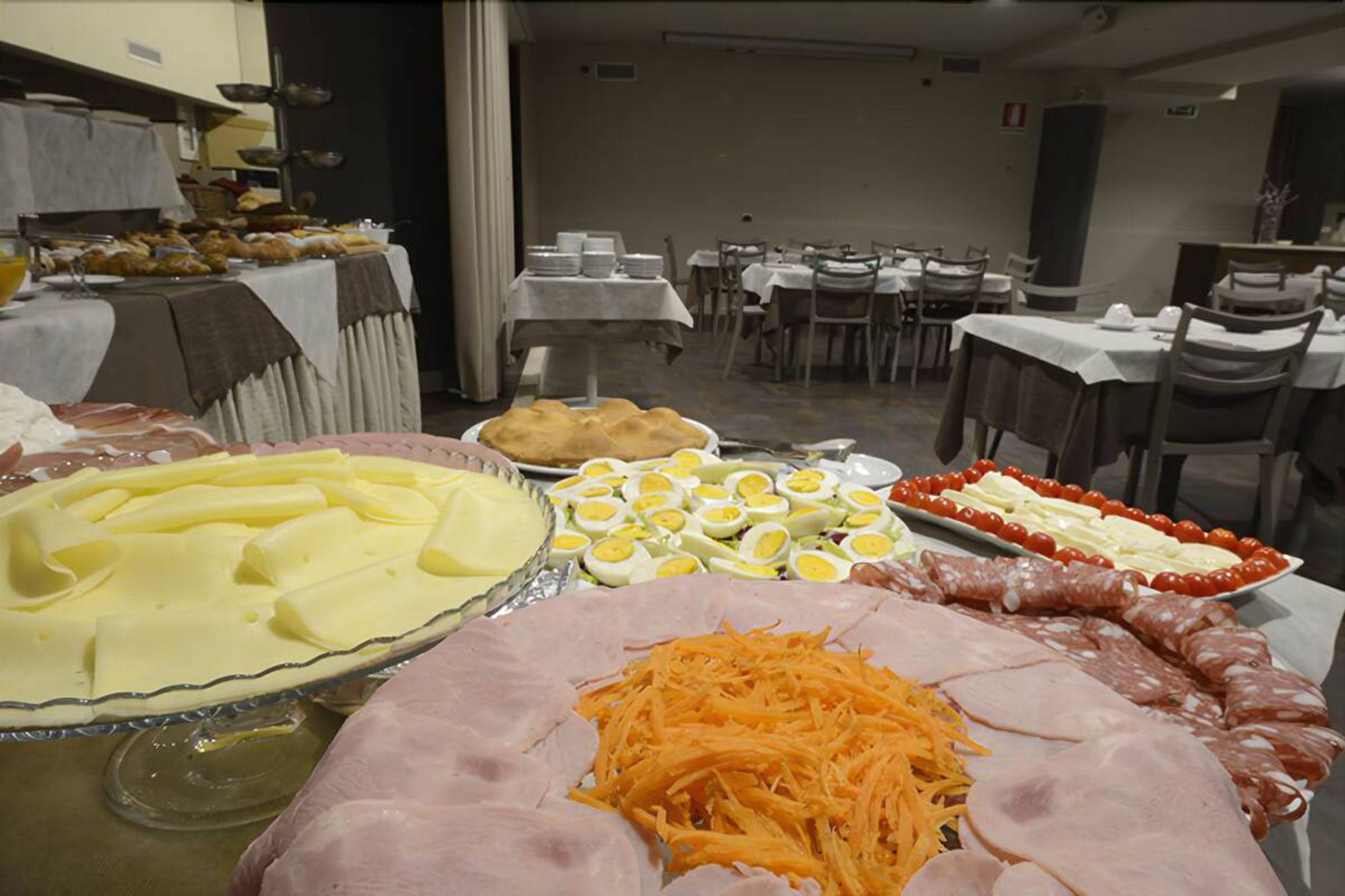 A buffet with various food items including sliced meats, cheese, and eggs.