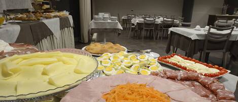 A buffet with various food items including sliced meats, cheese, and eggs.