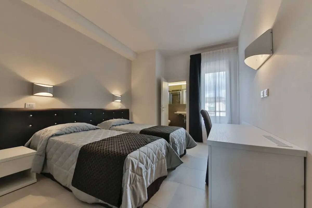 A hotel room with two beds, a desk, and a chair.