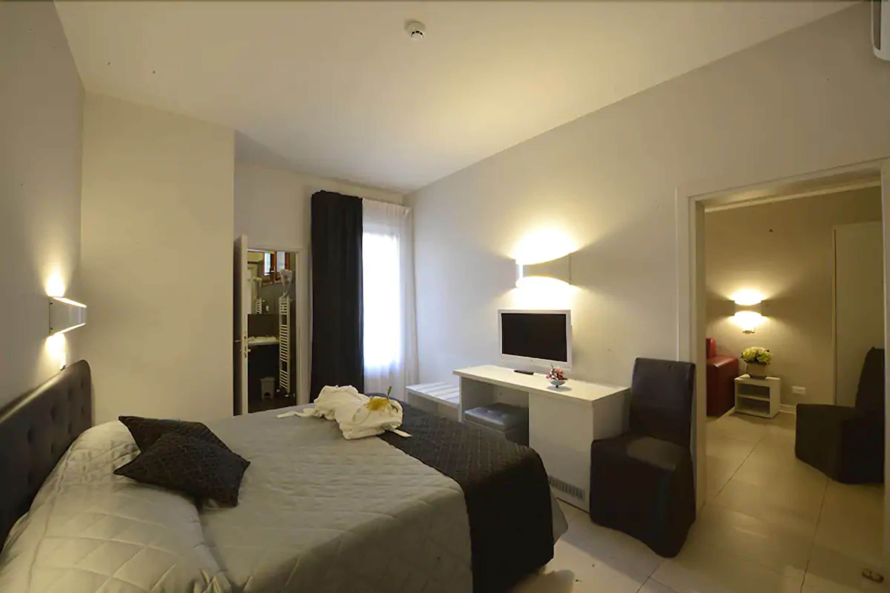 Una habitación de hotel con cama, escritorio, silla y televisión.