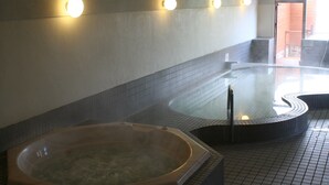 A hot tub in a tiled indoor area with a tiled floor and walls, and a doorway leading outside.