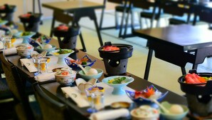 A dining area with tables set with various dishes and bowls, chairs, and a black tablecloth.