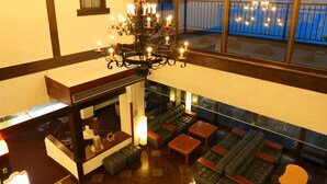 A spacious lounge area with multiple seating options, a chandelier, and large windows offering a view of the cityscape.