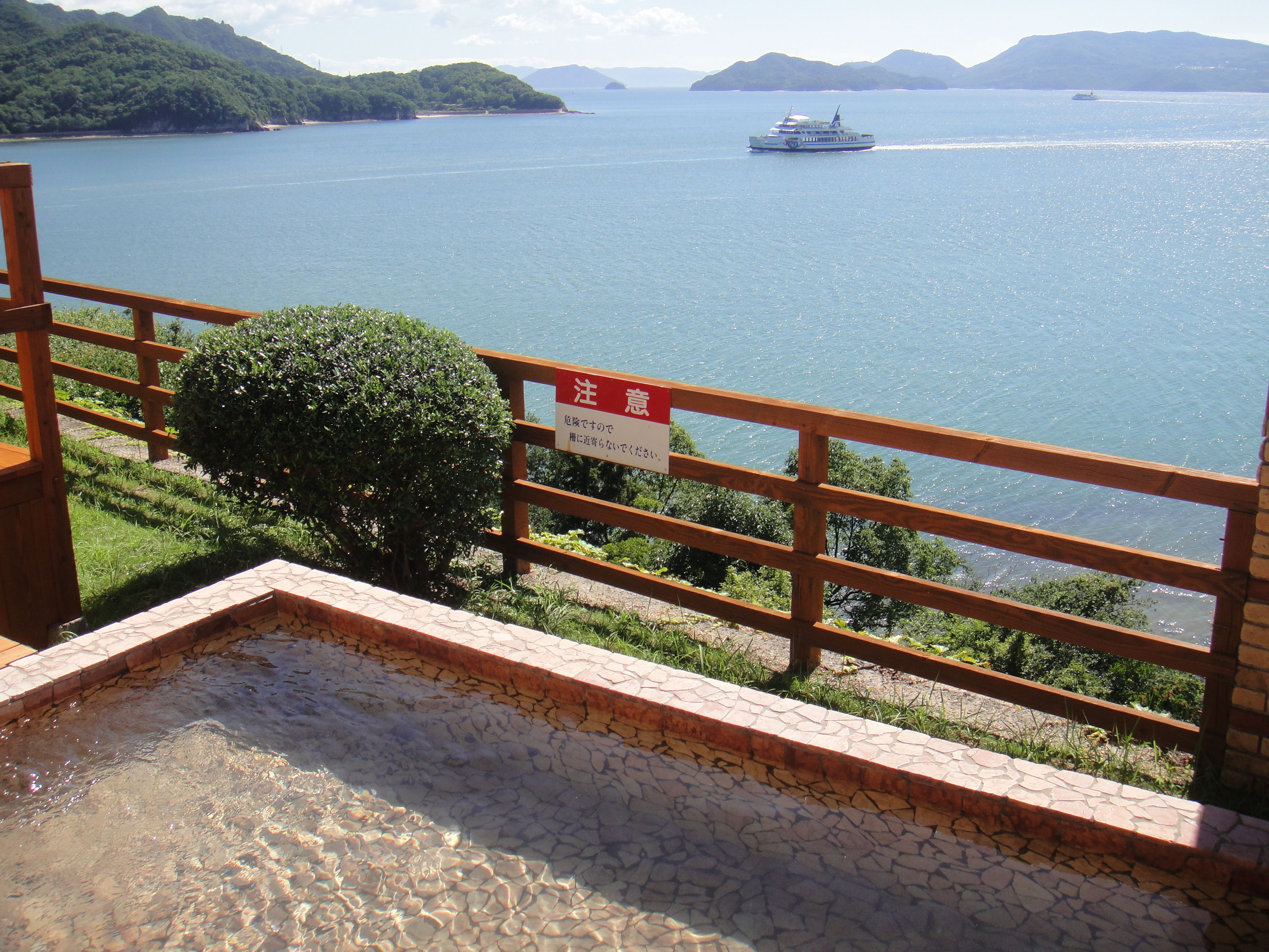 A wooden deck overlooking a body of water with a sign in a foreign language.