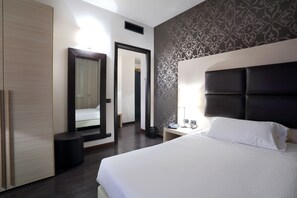A hotel room with a large bed, a bedside table with a lamp, a mirror, and a wardrobe. - Hotel La Torretta (Bollate)